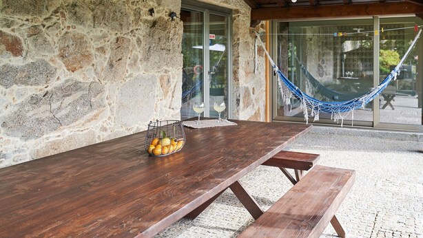 A stone wall, wooden table, and hammock in a covered outdoor area.