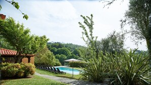 A pool area with lounge chairs, a pathway, and a view of the surrounding greenery.