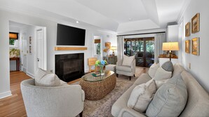 A spacious living room with a fireplace, comfortable seating, and a large TV. - Excellent Inlet Cove Cottage! Community Pool, Fishing Dock! (Johns Island)