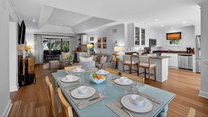A spacious living room with a dining area, kitchen, and a large window providing natural light. - Excellent Inlet Cove Cottage! Community Pool, Fishing Dock! (Johns Island)