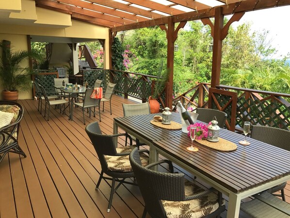 An outdoor patio with wooden flooring, wicker furniture, and a pergola.