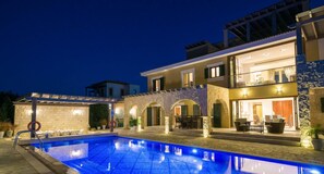Une maison à deux étages dotée d’une piscine, d’un espace salon extérieur et d’un patio couvert.