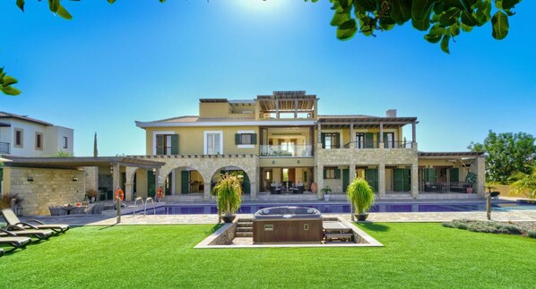 Une maison à deux étages avec une piscine, un espace salon extérieur et une pelouse bien entretenue.