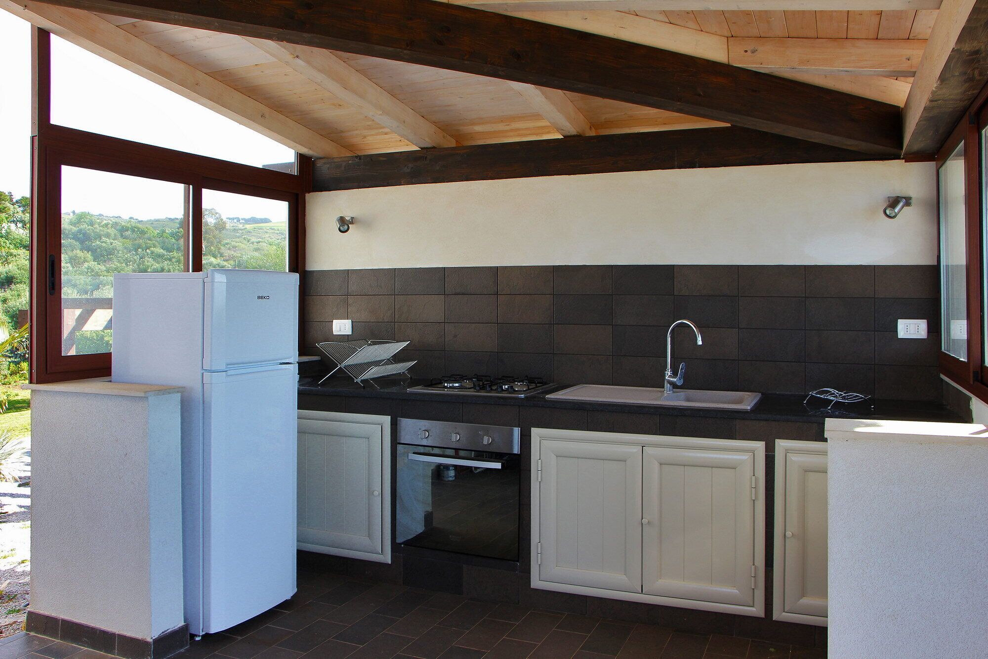 A compact kitchen with a built-in oven, a sink, and a refrigerator.