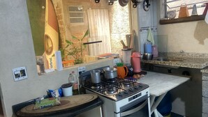 Cocina pequeña con estufa a gas, un lavabo y diferentes utensilios de cocina.