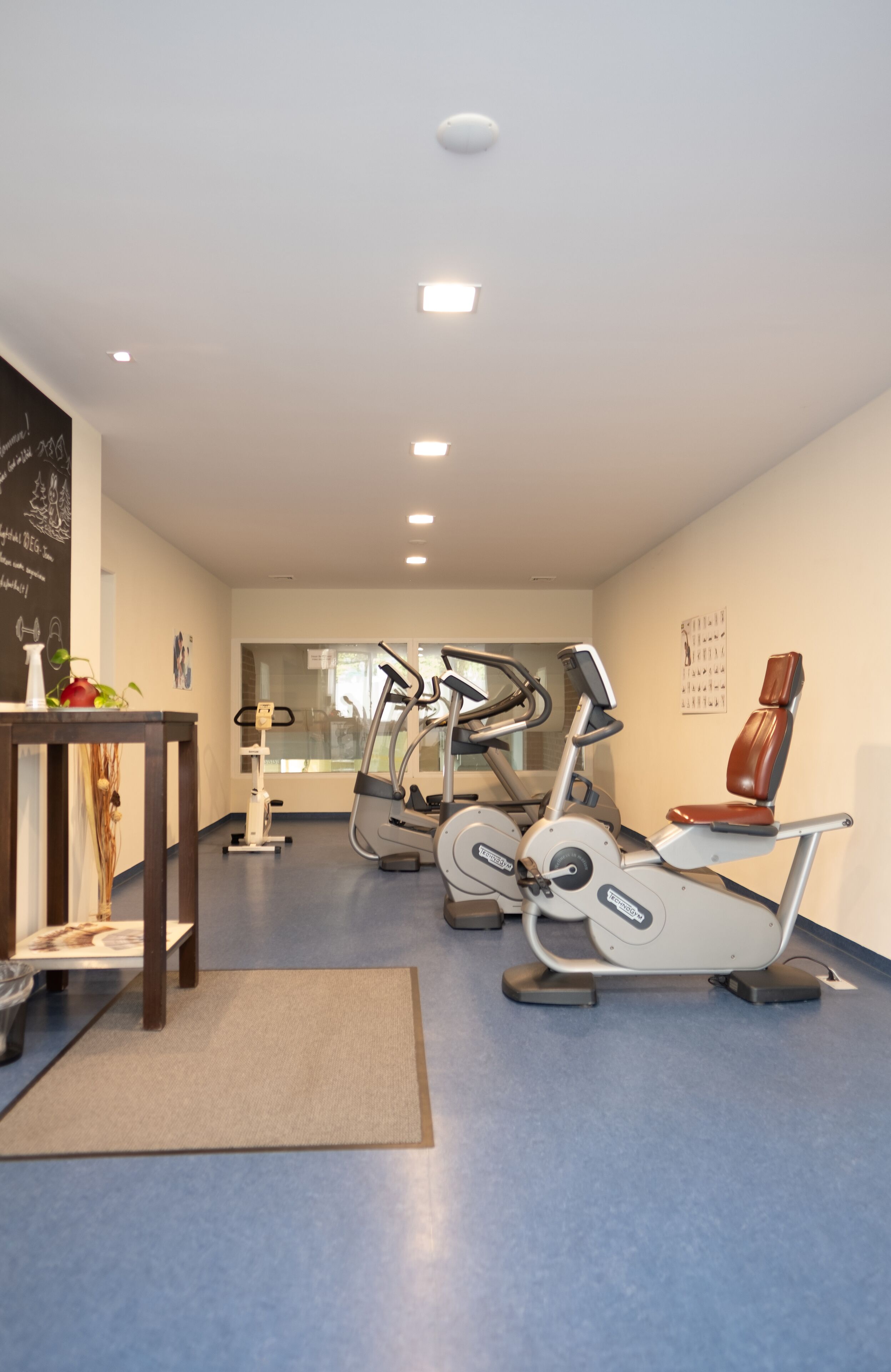 Un centre d'entrenament amb equips d'exercici, una recepció i una paret amb un cartell.