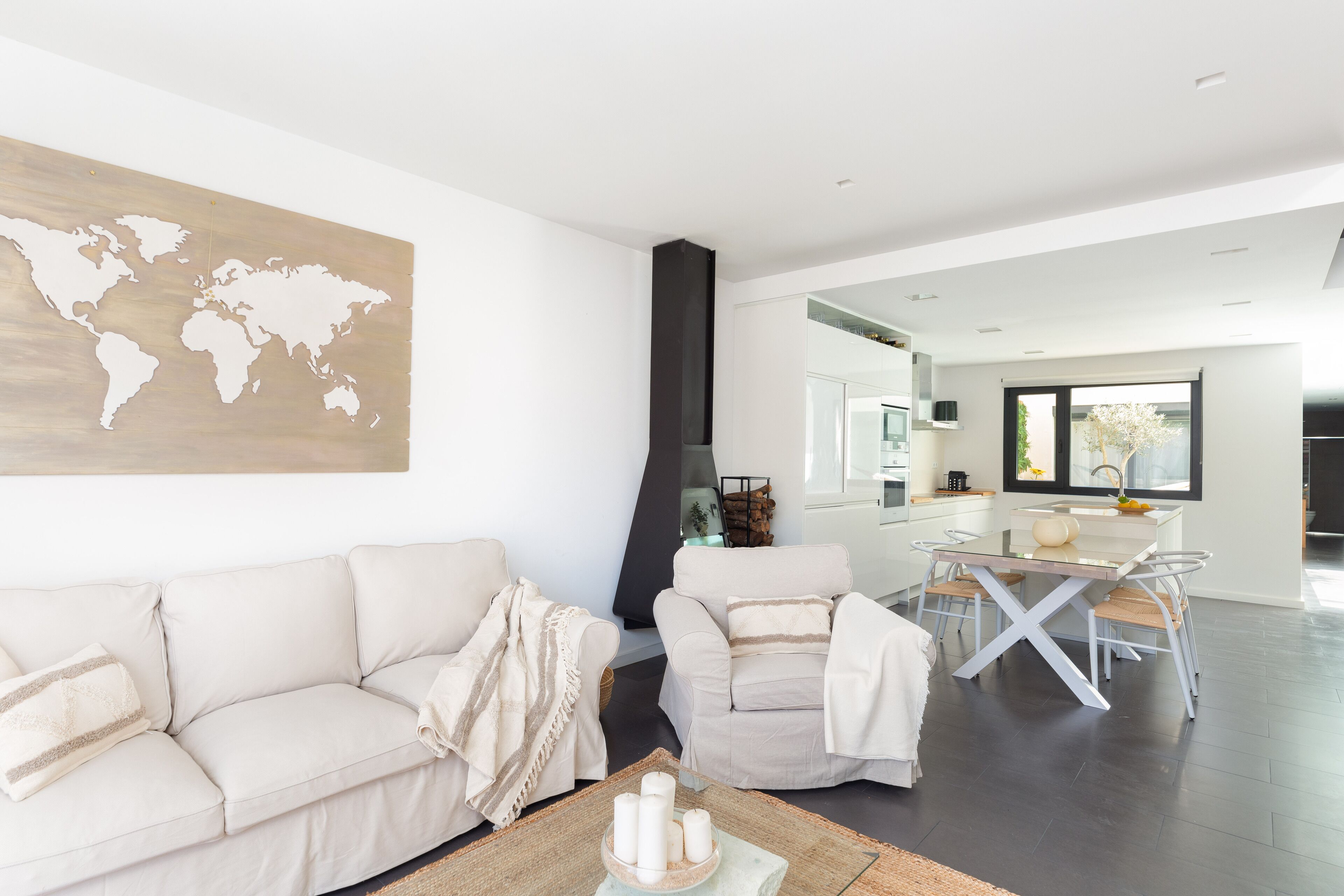 Una sala de estar moderna con un mapa del mundo en la pared, un sofá, una mesa de comedor y una cocina al fondo.