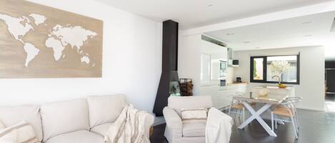 Una sala de estar moderna con un mapa del mundo en la pared, un sofá, una mesa de comedor y una cocina al fondo.