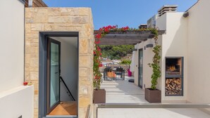 A narrow outdoor corridor with stone walls, a glass door, a wooden pergola with red flowers, and a wood-burning stove. - CASA DEL MAR 50m from the beach (Tamariu)