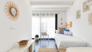 A bright, minimalist bedroom with a large window, a bed with white bedding, a small bedside table, and a woven basket. - CASA DEL MAR 50m from the beach (Tamariu)