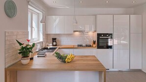 A modern kitchen with white cabinets, a wooden countertop, a built-in oven, and a hanging pendant light. - Villa Monte in Breg (Haus für 6 Personen) (Labin)