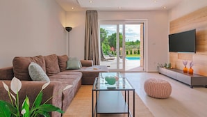 A modern living room with a sofa, a glass coffee table, and a television mounted on the wall. - Villa Monte in Breg (Haus für 6 Personen) (Labin)