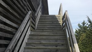 Un escalier en bois, doté d’une rampe, mène à un bâtiment.