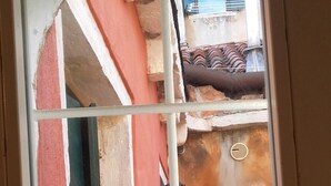 A window with a grid pattern, through which a building with red and beige walls is visible. - Sunny, quiet flat in the heart of Venice, near Rialto Bridge (Venezia)