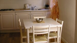 A kitchen with white cabinets, a stove, and a dining table with four chairs. - Sunny, quiet flat in the heart of Venice, near Rialto Bridge (Venezia)