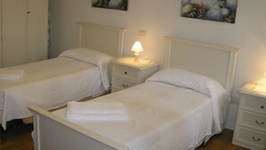A hotel room with two single beds, each with a nightstand and a lamp. There are paintings on the wall above the beds. - Sunny, quiet flat in the heart of Venice, near Rialto Bridge (Venezia)