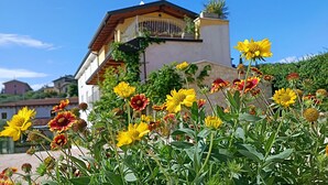 Uma casa com varanda e jardim com flores amarelas e vermelhas.