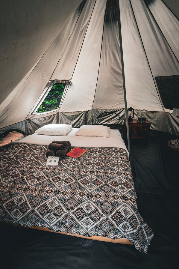 A tent with a bed, a welcome mat, and a window.