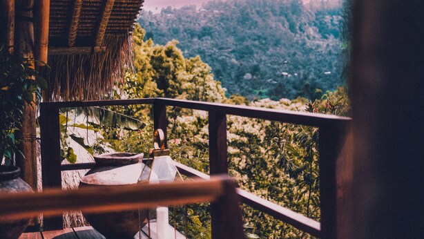 A wooden balcony with a view of a lush green landscape.