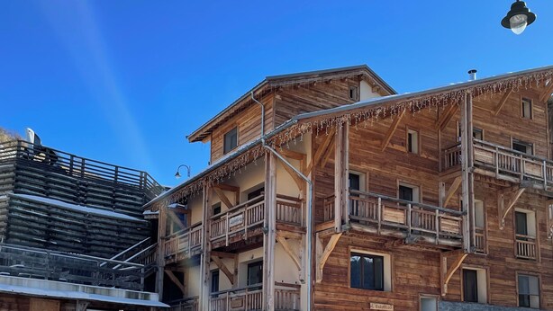 A multi-story wooden building with balconies and a covered entrance.