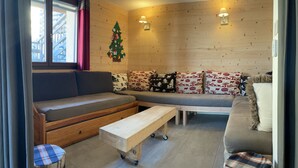 A cozy room with a wooden wall, a sofa with patterned cushions, a bench, and a small table.