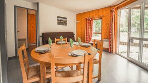 Un comedor con una mesa redonda de madera dispuesta para cuatro personas, rodeada de sillas de madera con asientos de mimbre.