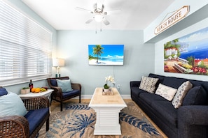 A living room with a ceiling fan, a TV, a coffee table, and a couch.