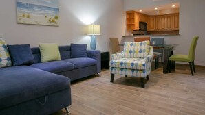 Una sala de estar con sofá, sillón y un cuadro en la pared.