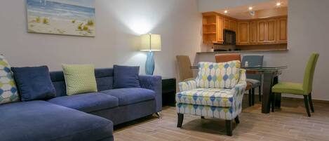 A living room with a sofa, armchair, and a painting on the wall.