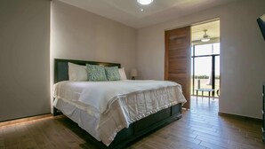 Un dormitorio con una cama grande, cabecera de madera, ventana con vistas y puerta que da a un espacio exterior.