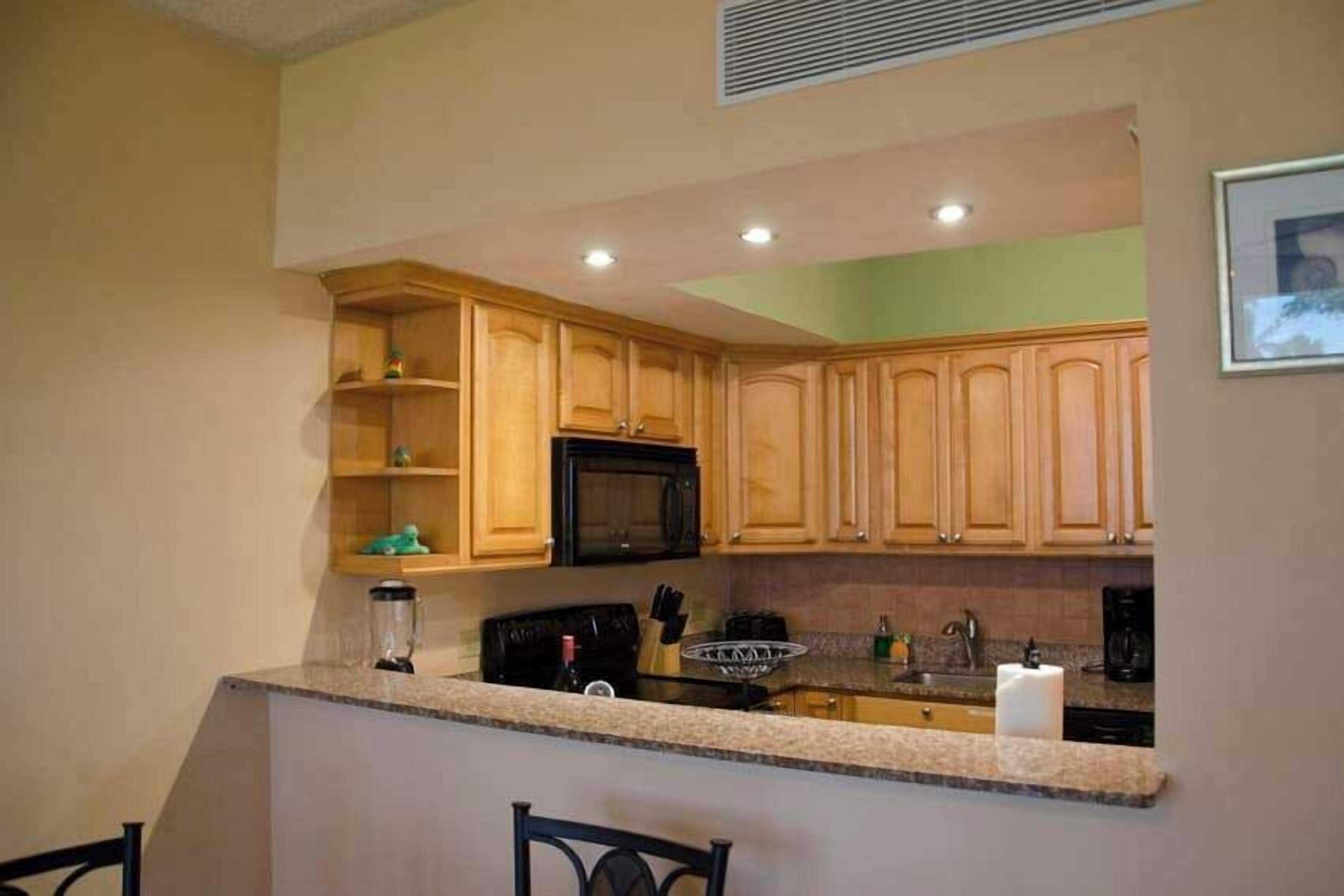 A kitchen with wooden cabinets, a microwave, and a granite countertop.