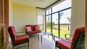 Una habitación con un sofá rojo, dos sillones y una mesita.