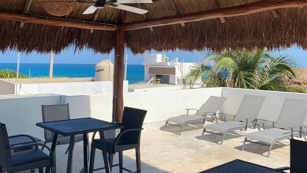A rooftop terrace with a thatched roof, outdoor seating, and a view of the ocean. - Penthouse - Casa Mango Great location! (Isla Mujeres)