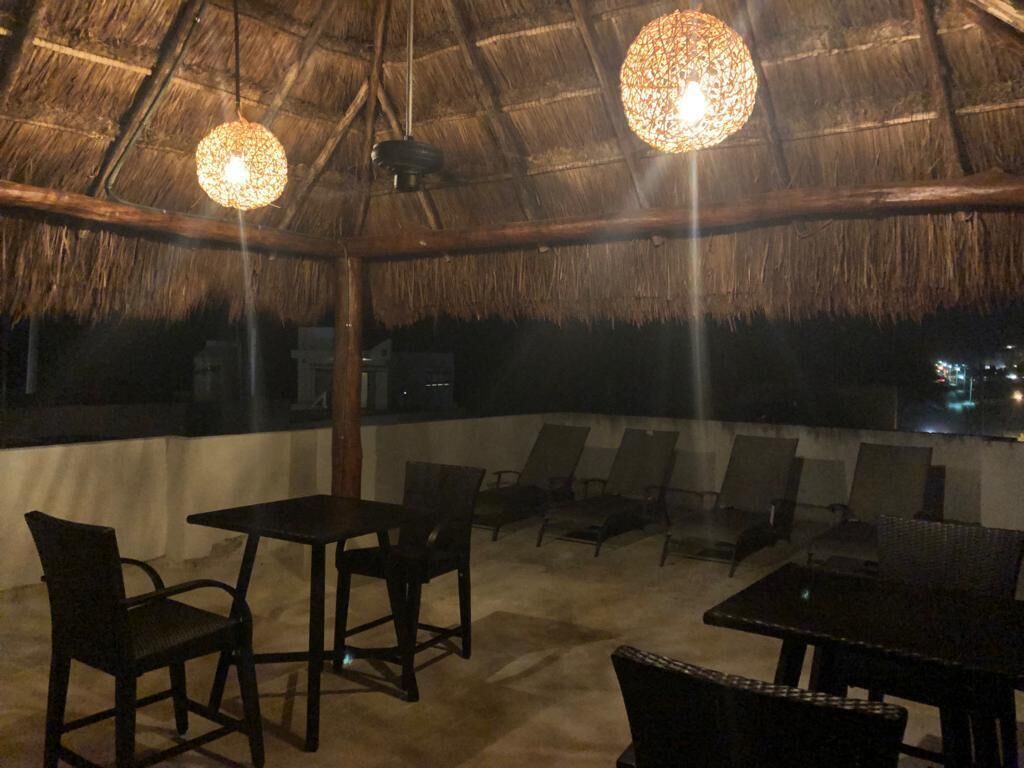 An outdoor seating area with thatched roof, tables, and chairs.