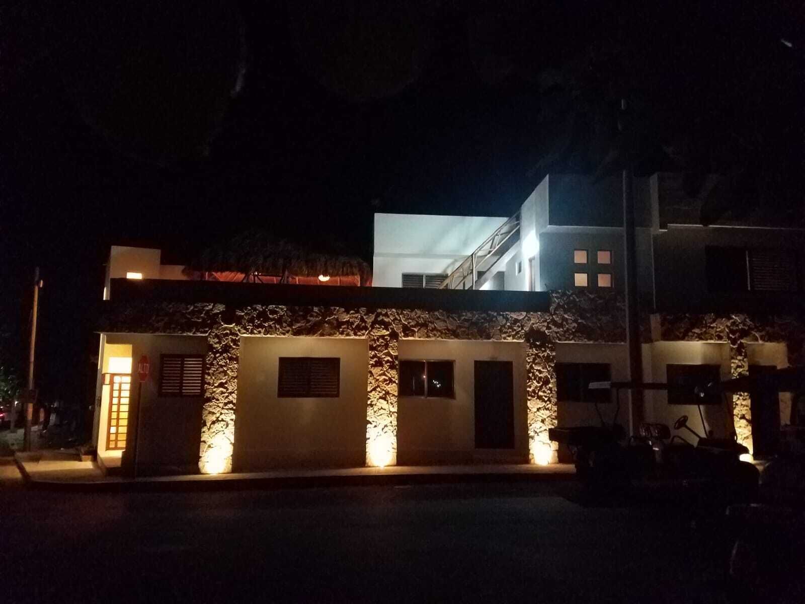 Un bâtiment moderne avec une façade en pierre, de nombreuses fenêtres et une entrée illuminée.