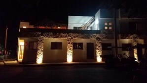 A modern building with a stone facade, multiple windows, and a lit entrance. - Penthouse - Casa Mango Great location! (Isla Mujeres)
