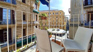 A balcony with wicker chairs and a table, overlooking a cityscape with historic buildings. - B&B Quattro Palazzi center of Naples, in the heart of Naples. (Napoli)