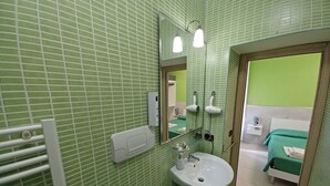 A bathroom with green tiled walls, a white sink, a mirror, and a towel rack. - B&B Quattro Palazzi center of Naples, in the heart of Naples. (Napoli)