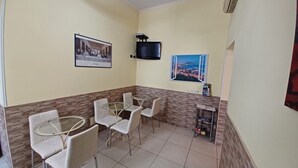 A dining area with round tables and chairs, a mounted TV, and a framed picture on the wall. - B&B Quattro Palazzi center of Naples, in the heart of Naples. (Napoli)