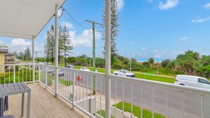 A balcony with a view of a road, cars, and greenery.