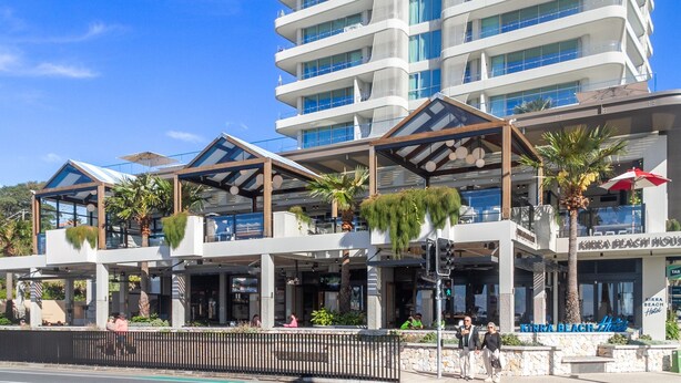 A modern hotel with multiple floors, outdoor seating areas, and a prominent sign for 'KIRRA BEACH Hotel'.