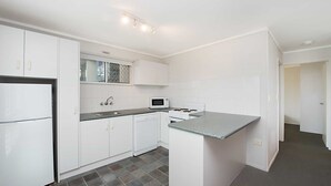 A compact kitchen with white cabinets, a microwave, a stove, and a sink.