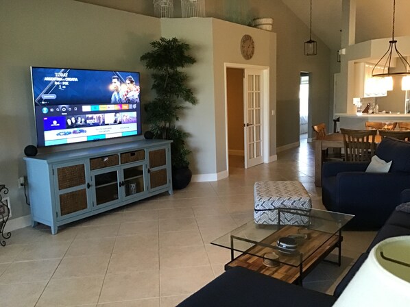A living room with a television, a sofa, a coffee table, and a potted plant. - Beautiful Condo in Tranquil, Tropical Setting in Flamingo Fairways 2 (Naples)