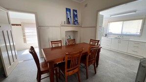 Un comedor con mesa y sillas de madera, una cocina con armarios blancos y una obra de arte en la pared.