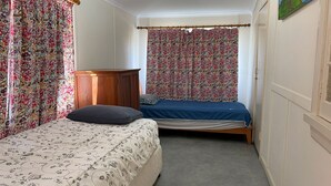 Un dormitorio con cama, armario de madera y cortinas con estampado floral.