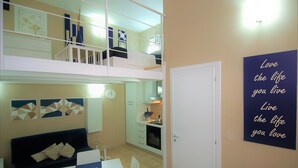 A compact apartment with a dining area, kitchenette, and a balcony.
