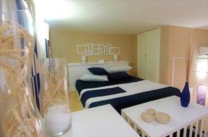 A neatly arranged hotel room with a bed, bedside tables, and a decorative wall piece. - Virna House in Castellammare del Golfo (Scopello)