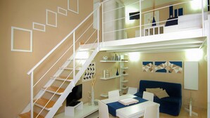 A modern living room with a staircase, a dining area, and a sofa.