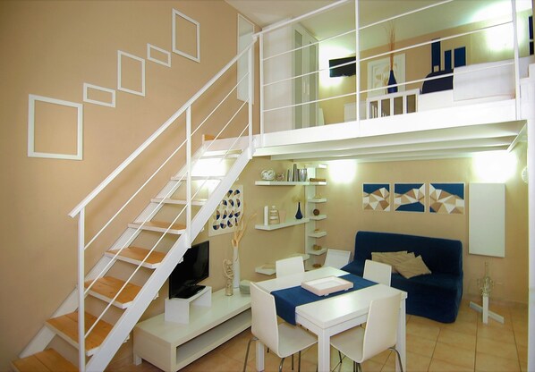 A modern living room with a staircase, a dining area, and a sofa. - Virna House in Castellammare del Golfo (Scopello)