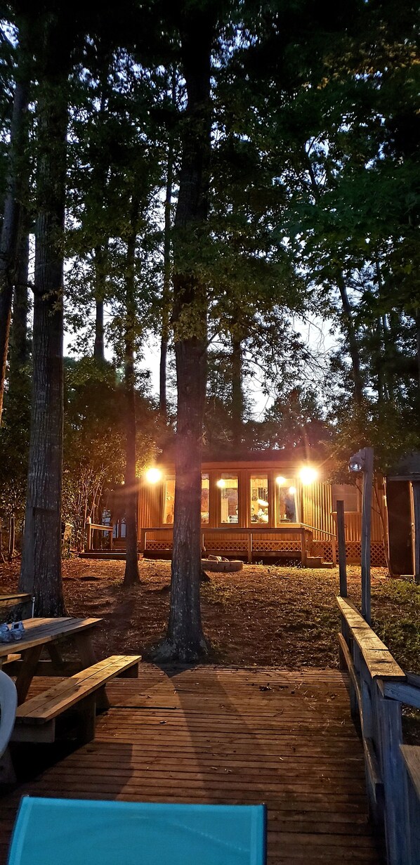 A wooden deck leading to a cabin with a porch, surrounded by tall trees. - Rustic Waterfront Cabin on Toledo Bend Lake (Hemphill)